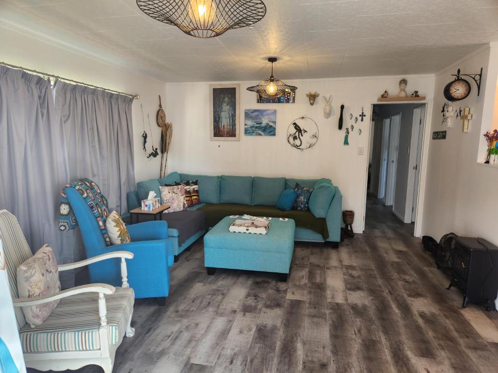 sala de estar con sofá azul y sillas en Rings Road Bach en Coromandel Town