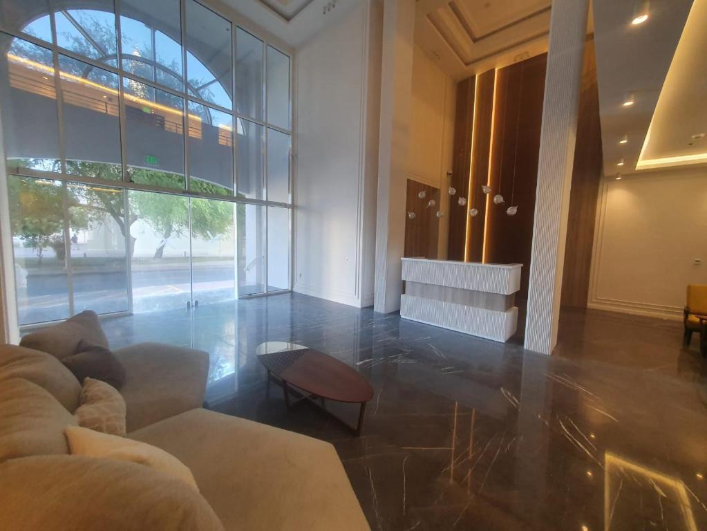 sala de estar con sofá y ventana grande en Terminal Inn Airport Hotel & Apartment, en Doha