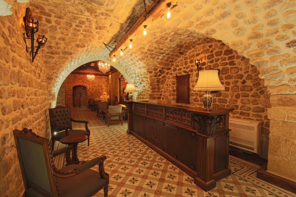 a living room with a stone wall and a table and chairs at Sam Franss Boutique Otel in Hatay