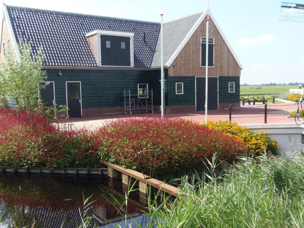 Spacious Holiday Home in the Beemster near a Windmill في Middenbeemster: منزل خشبي كبير مع شرفة وحديقة