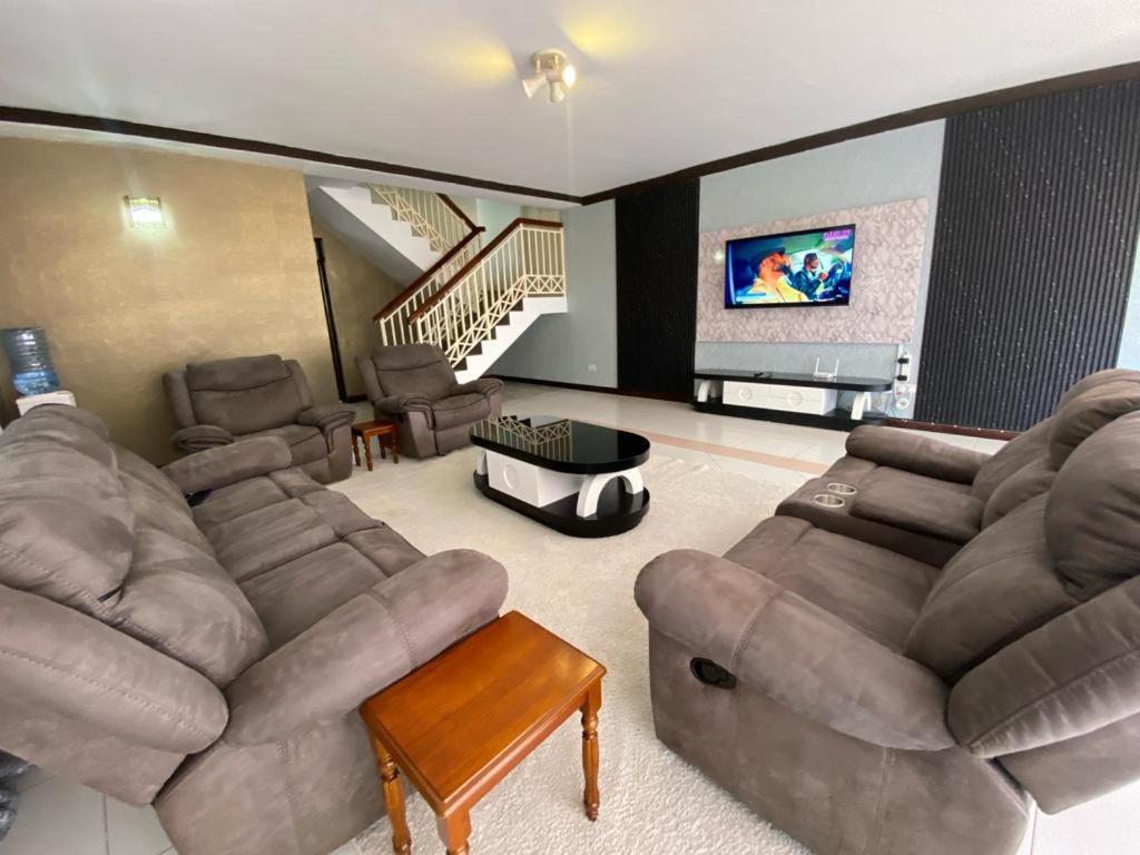 a living room with couches and a flat screen tv at Barzoo Homes in Kisumu