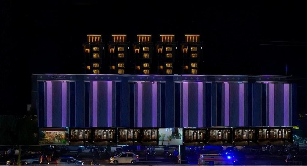 a lit up building with a tall building in the background at Zip By Spree Hotels Bhopal in Bhopal