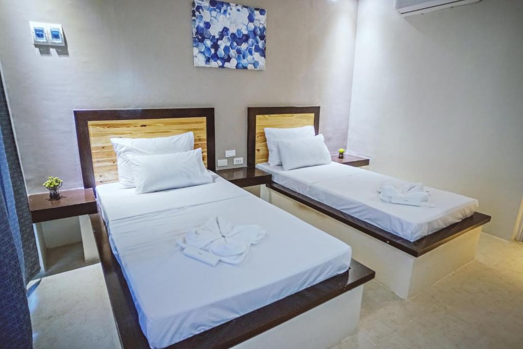 2 camas en una habitación con sábanas blancas en G Hotel, en Dauis