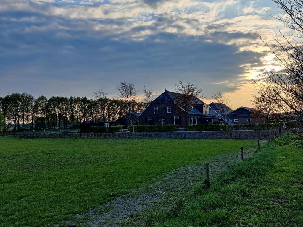 a large field with a house in the background at Spacious farmhouse in Silvolde with garden in Silvolde