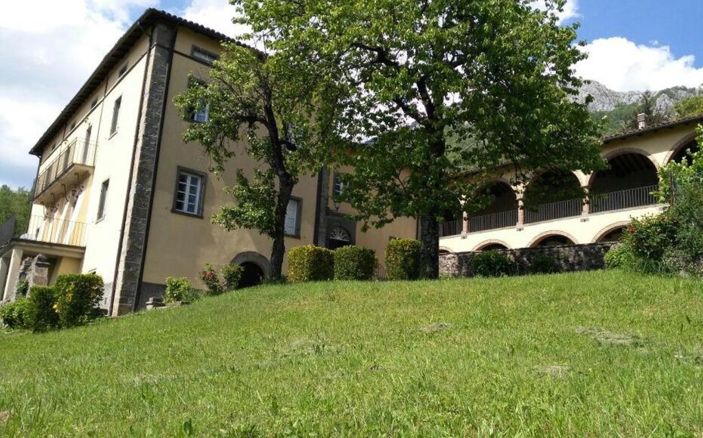 Apartment Casa Gianfrati في Corfino: مبنى كبير على تلة عشبية مع شجرة