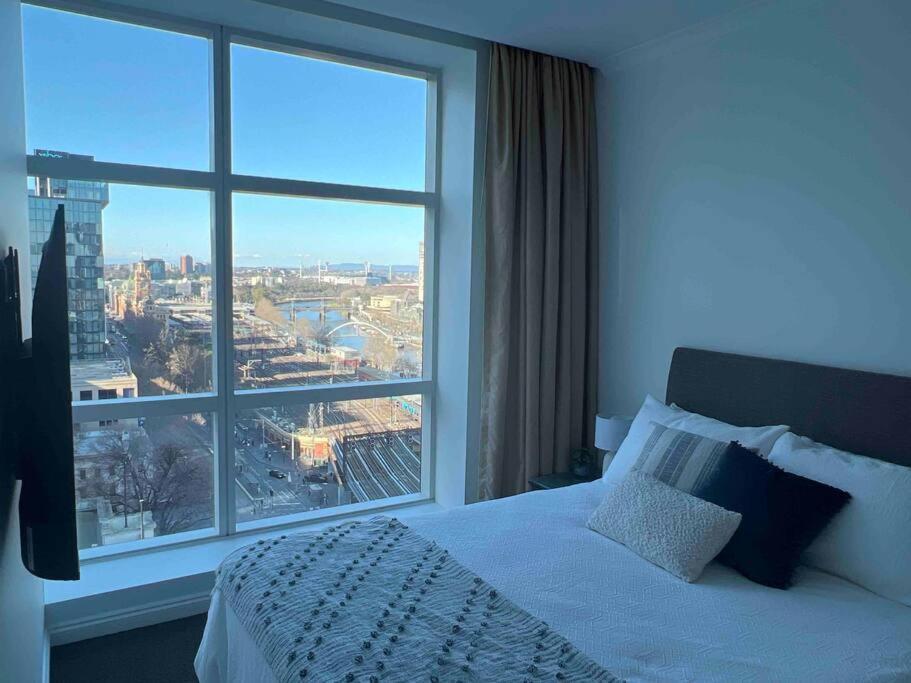 een slaapkamer met een bed en een groot raam bij Exclusive Suite CBD Riverviews - ParkingOnsite in Melbourne