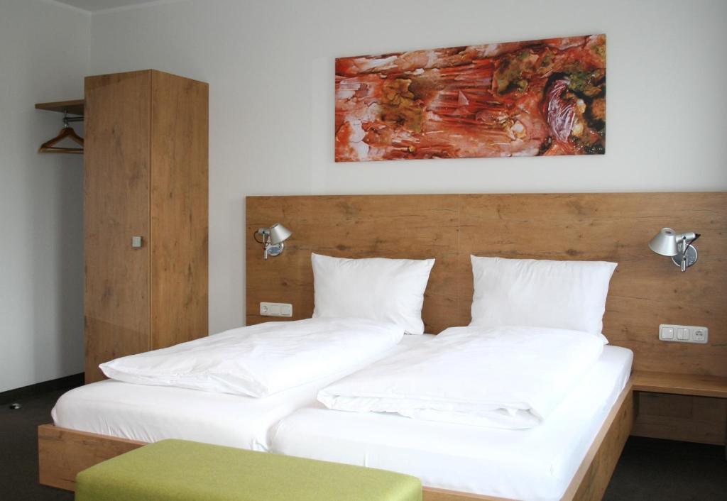 2 Betten mit weißer Bettwäsche und einem Kopfteil aus Holz in der Unterkunft Lahn Hotel in Biedenkopf