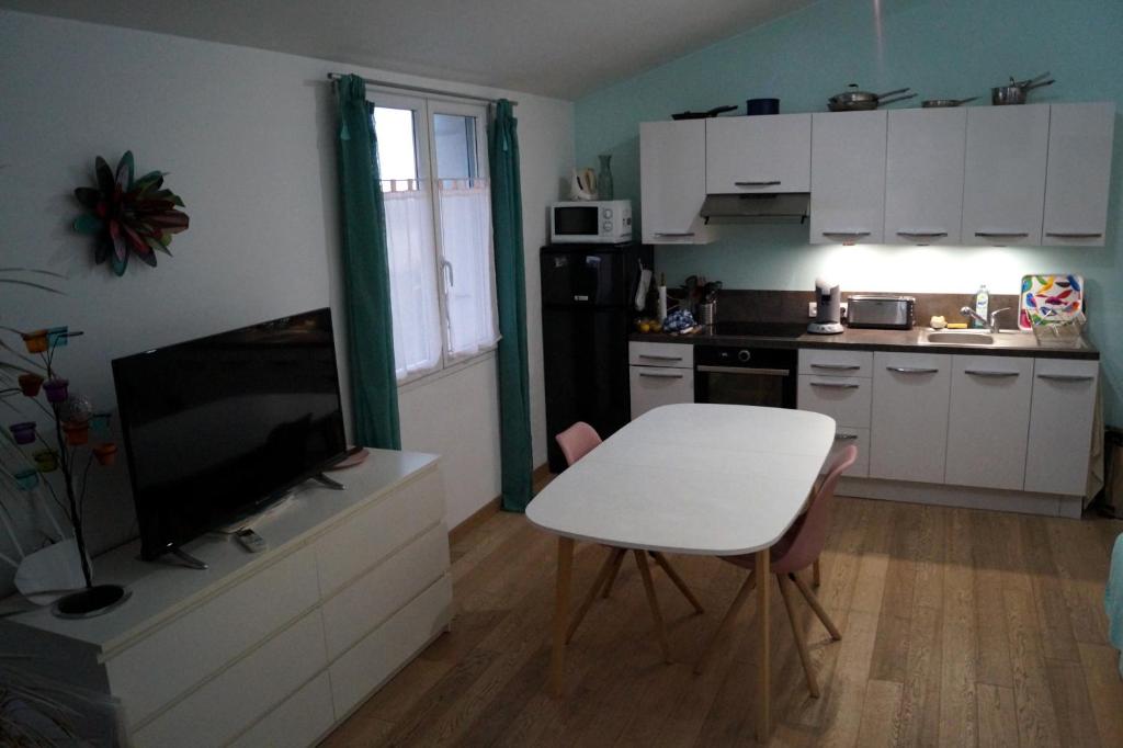 une cuisine avec une table blanche et une télévision sur une armoire dans l'établissement appartement dans villa aquarelle, à Biguglia