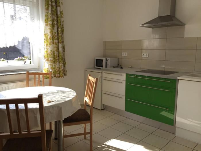 cocina con mesa y armario verde en Lamar Apartman, en Kapuvár