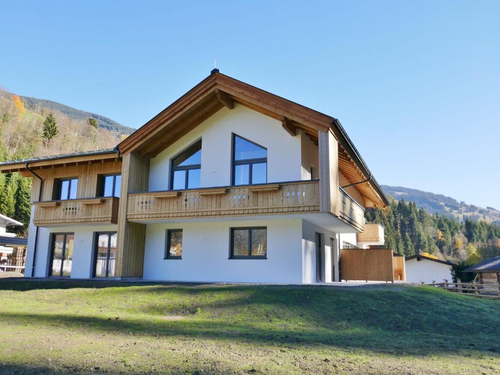 a house with a wooden roof on a grass field at Luxury Chalet in Saalbach Hinterglemm with Sauna in Saalbach Hinterglemm