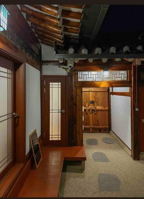 a living room with wooden walls and a room withwindows at Gilgaon Hanok Stay in Seoul