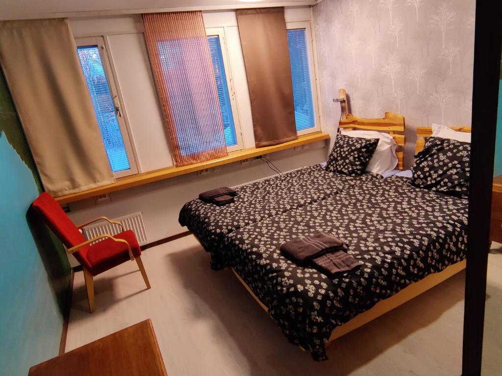 a bedroom with a bed and a chair and windows at Jaala Hotel in Kouvola