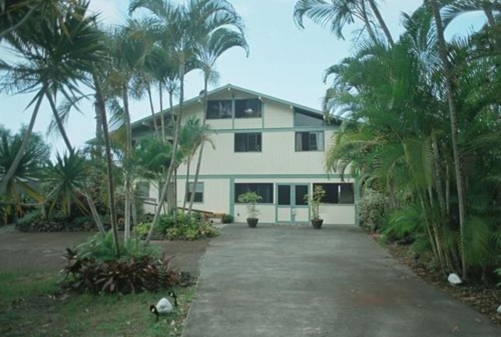 a large white house with palm trees in front of it at Hale-Hoola B & B in Captain Cook
