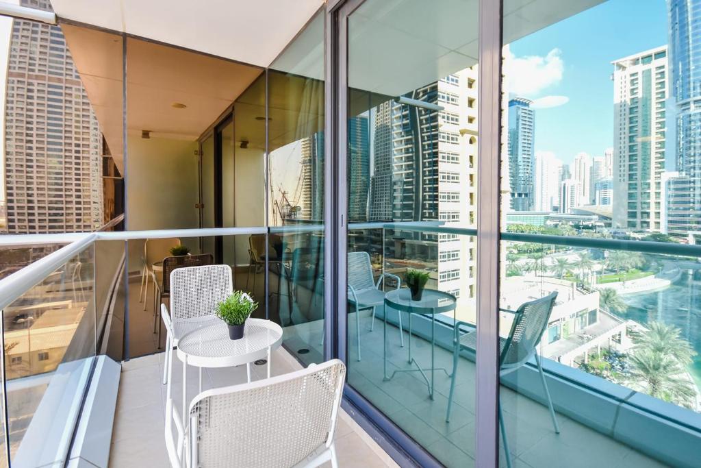 uma varanda com mesas e cadeiras e vista para a cidade em LUXFolio Retreats Beautiful JLT 1BR Apartment em Dubai