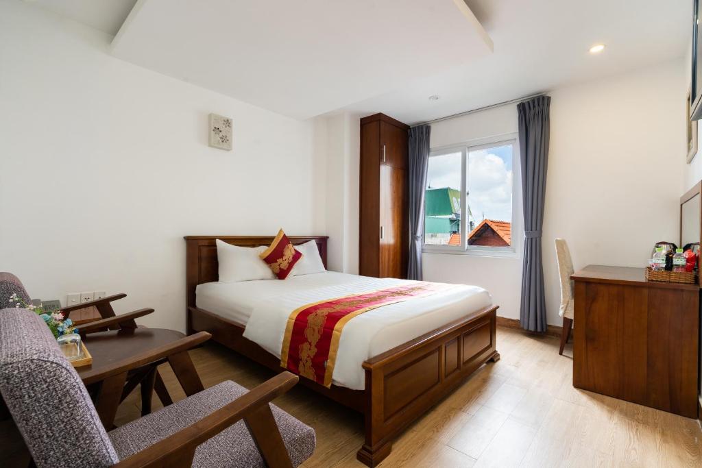 Schlafzimmer mit einem Bett, einem Schreibtisch und einem Fenster in der Unterkunft King Hotel Saigon Airport in Ho-Chi-Minh-Stadt