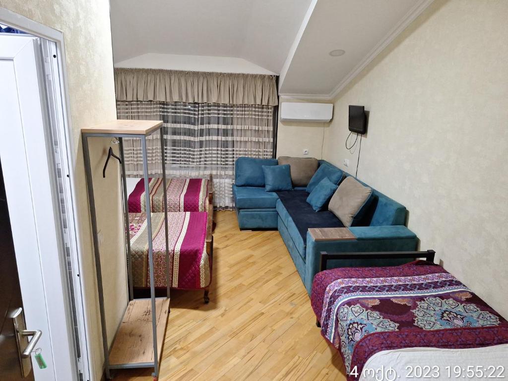 a living room with a blue couch and a bed at GUEST HAUSE & HOSTEL 15a in Kʼutʼaisi