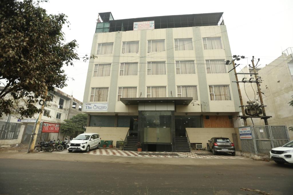 a white building with cars parked in front of it at Hotel Orchid & Banquet in Agra