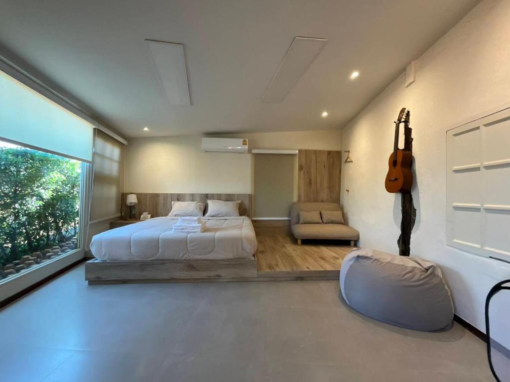 a bedroom with a bed and a guitar on the wall at กระบองแพะ in Ban Nong Khwang