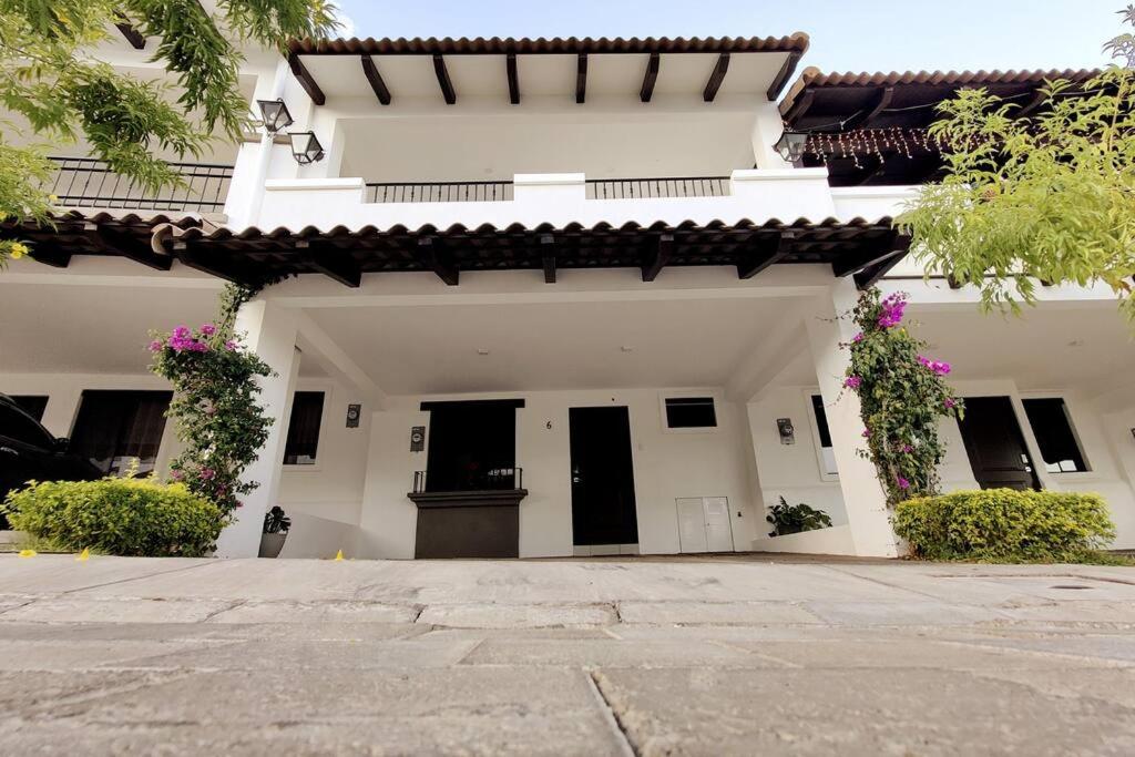 a white house with black doors and flowers at Cómoda casa en Residencial San Andrés in San Miguel