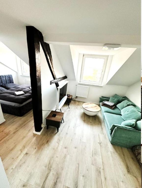 a living room with a green couch and a bed at Altbauloft, frisch saniert, mitten in Hameln in Hameln