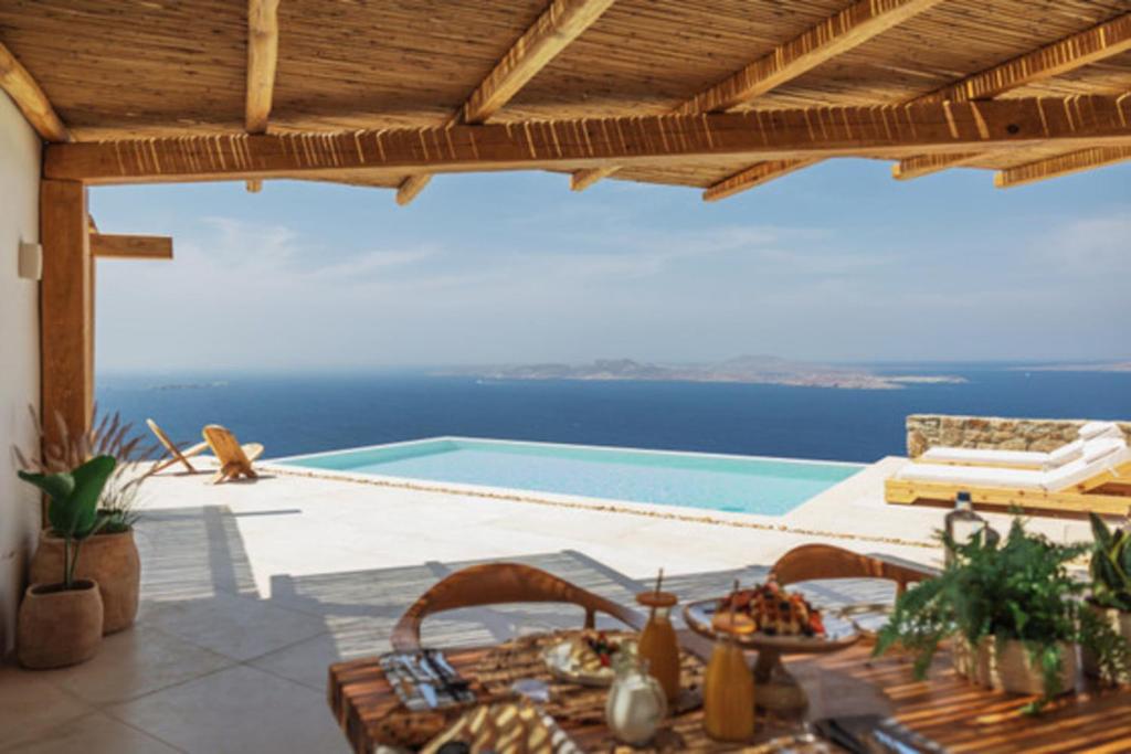 a patio with a table and a swimming pool at Birdhouse Private Luxury Suite in Agios Ioannis Mykonos