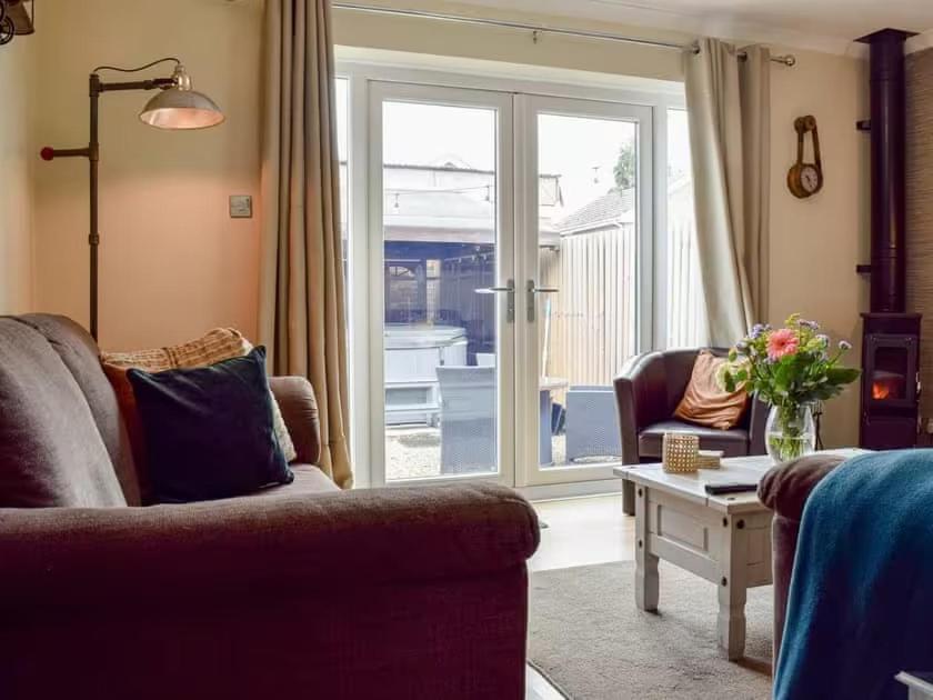 a living room with a couch and a sliding glass door at Little Lodge Walcote Lutterworth in Lutterworth