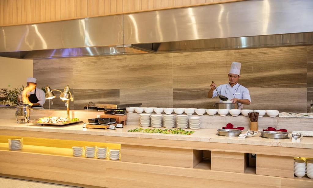 a chef standing in a kitchen preparing food at Cam Ranh Riviera Beach Resort & Spa in Cam Ranh