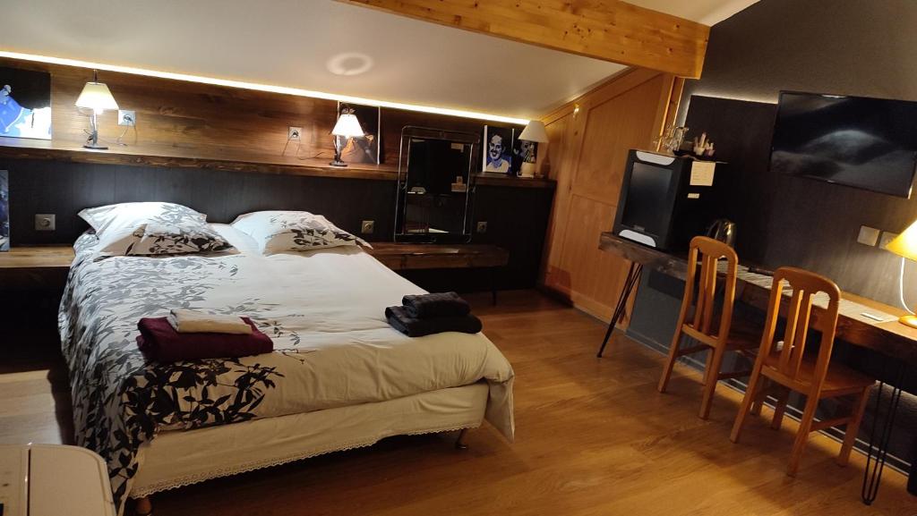 a bedroom with a bed and a desk and a kitchen at Logis auberge de la Poirie in Tendon