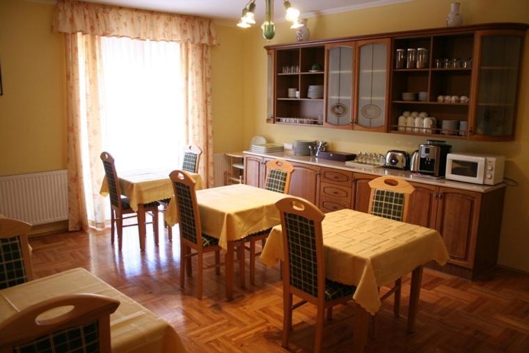 a kitchen with two tables and chairs and a kitchen with a microwave at Euro Panzio in Debrecen