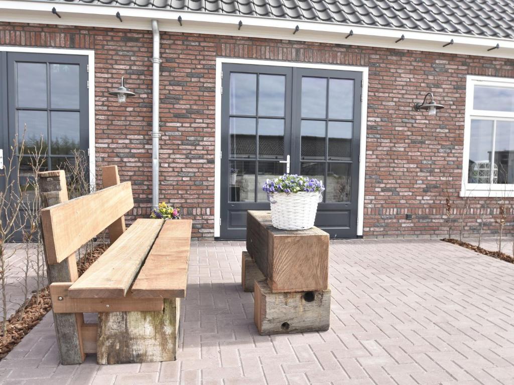 un patio con un banco y una maceta de flores en Studio Hazenborgh in Callantsoog near the sea, en Callantsoog
