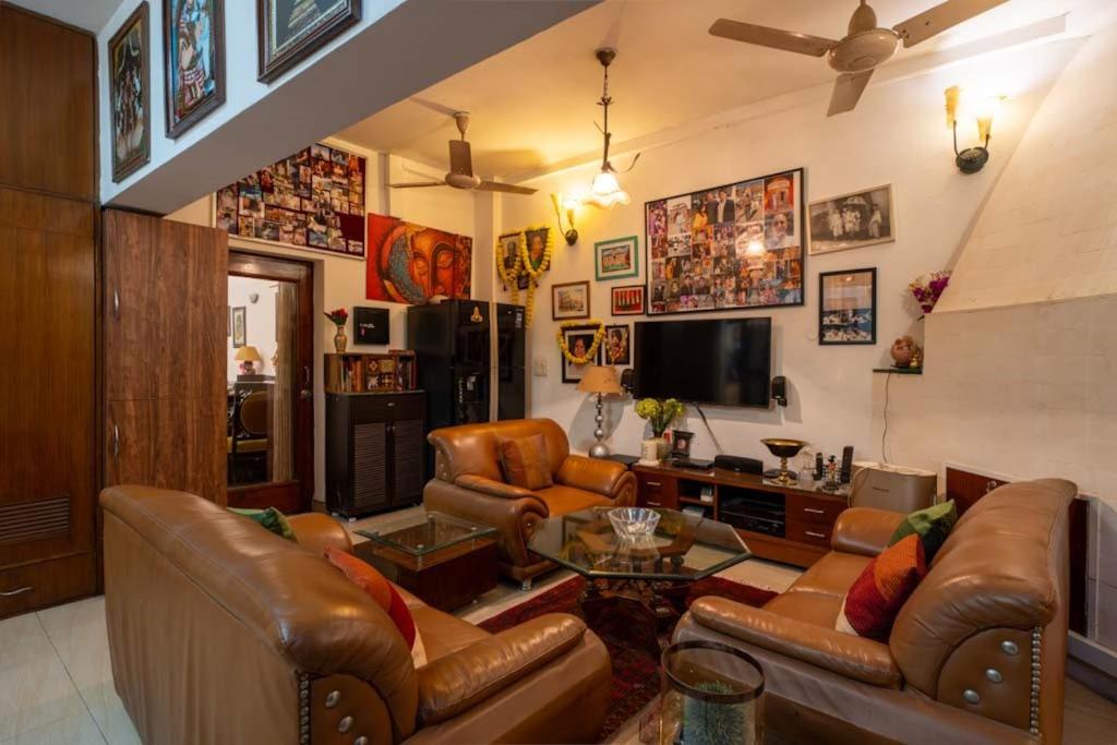 sala de estar con sofás de cuero y TV en Bunny Villa en Nueva Delhi