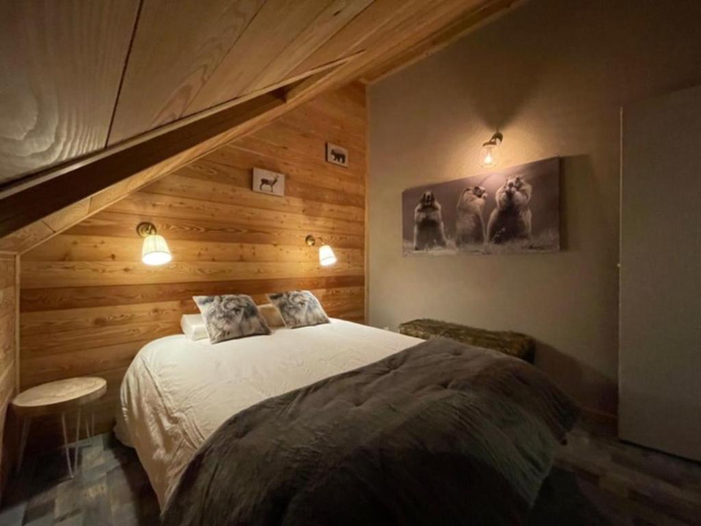 a bedroom with a bed with a wooden wall at Chez nous piste noire in Briançon
