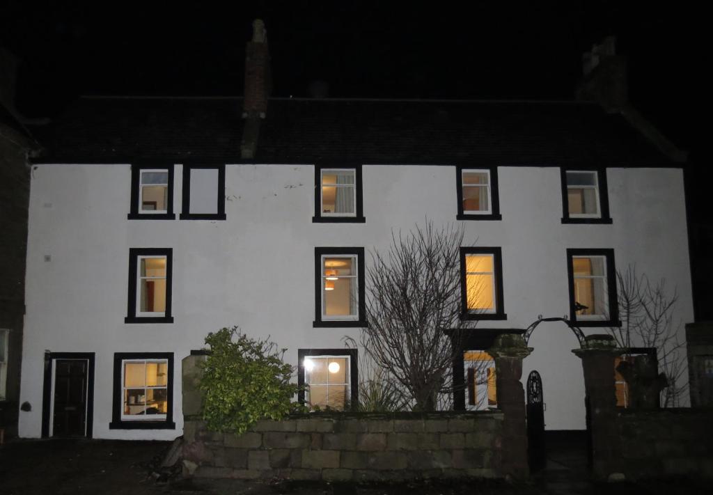 een wit huis met 's nachts verlichte ramen bij The Heritage Guest House in Montrose