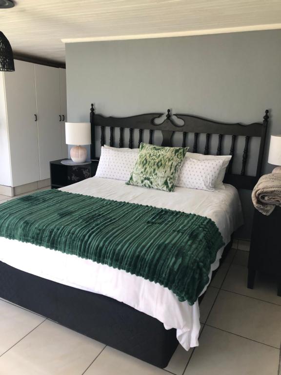 a bedroom with a large bed with a green blanket at Kieron's Cottage in Lydenburg