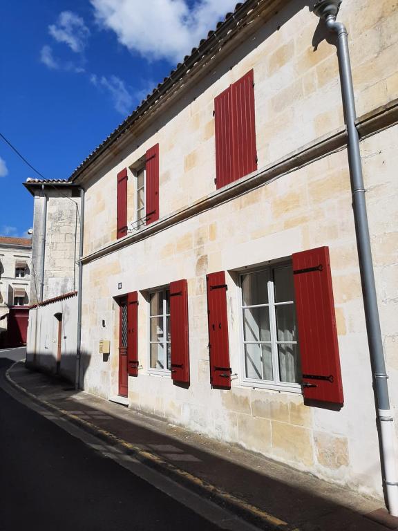 a building with red doors and windows on a street at ON LOGE A PIED ET A CHEVAL in Jonzac