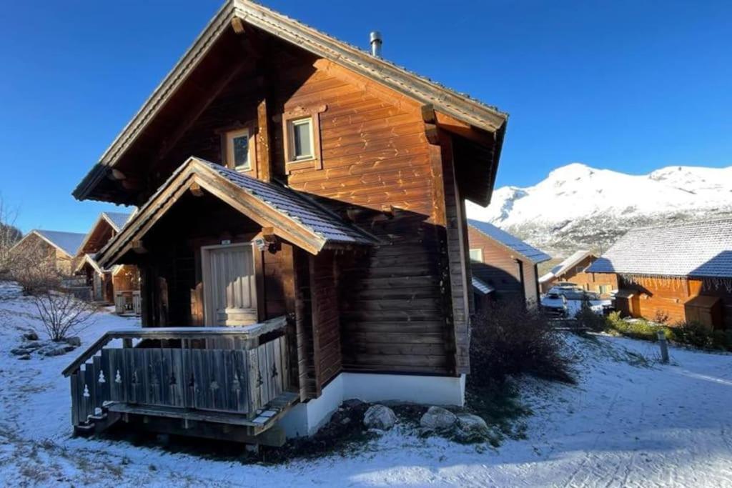 une cabane en rondins avec une terrasse couverte dans la neige dans l'établissement Chalet individuel, piscine sauna, à Saint-Étienne-en-Dévoluy
