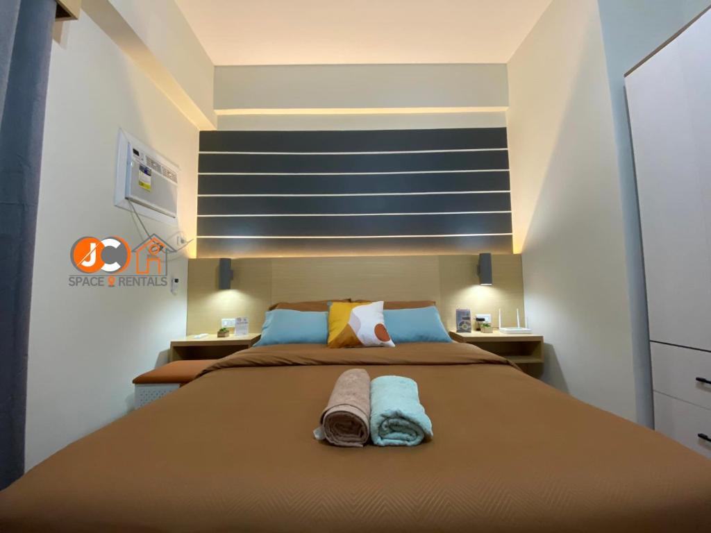 ein Schlafzimmer mit einem großen Bett mit zwei Handtüchern darauf in der Unterkunft JC SpaceRentals 127B Amani Grand Resort Residences, balcony pool view, Ground floor, 5 mins frm airport, free wifi, Netflix in Pusok