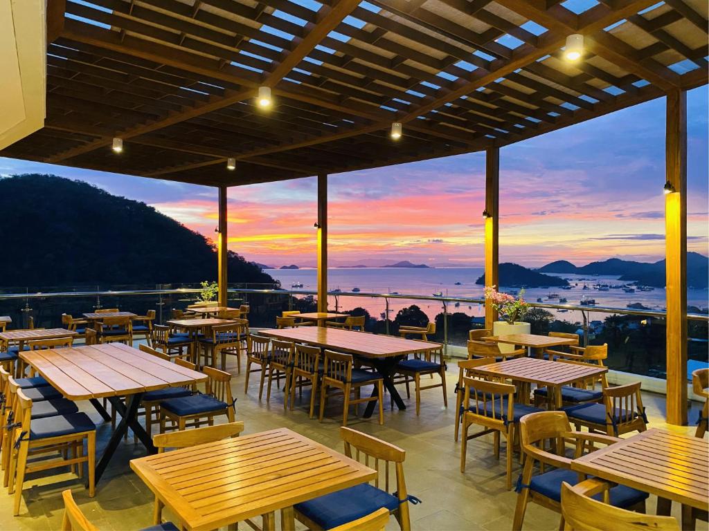 ein Restaurant mit Tischen und Stühlen und einem Sonnenuntergang in der Unterkunft Zasgo Hotel in Labuan Bajo