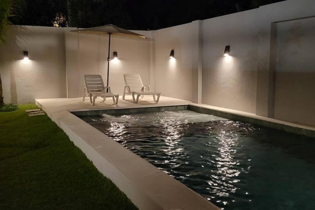 dos sillas y una sombrilla junto a una piscina por la noche en Moderna casa en San Bernardino!! en San Bernardino
