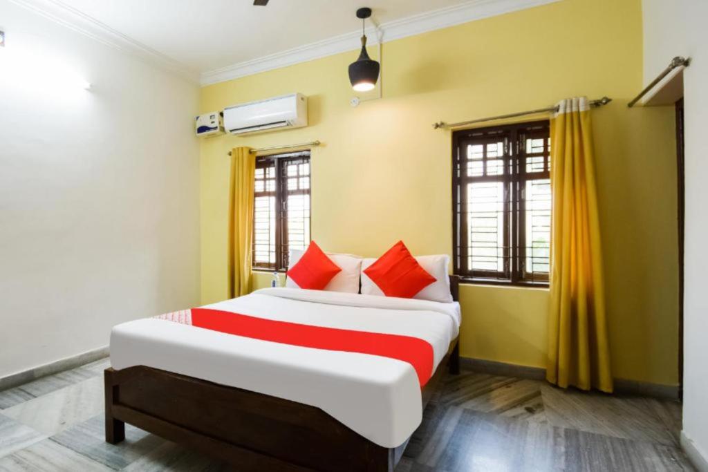 a bedroom with a large bed with red pillows at Goroomgo Mks Inn Bhubaneswar in Bhubaneshwar