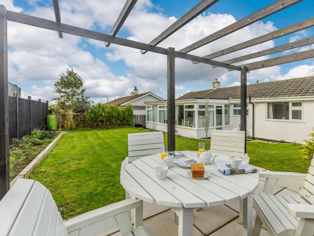 a patio with white chairs and a white table at 2 Bed in Bude 90312 in Bude