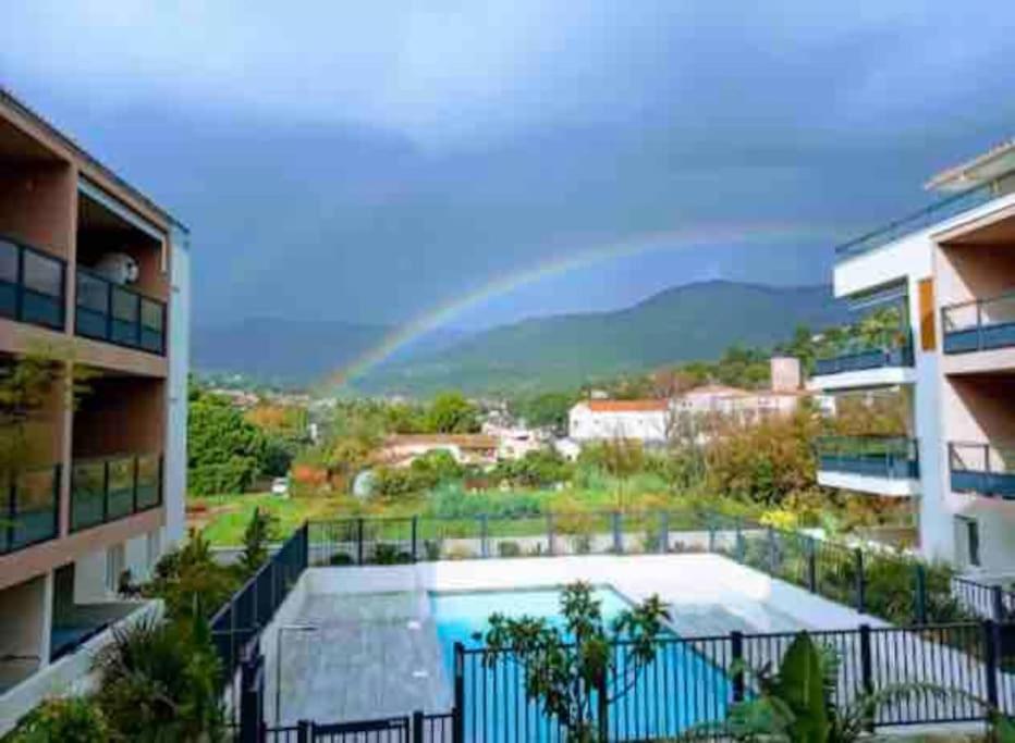 un arc en ciel au-dessus d'une ville avec piscine dans l'établissement Magnifique appartement au Lavandou, au Lavandou
