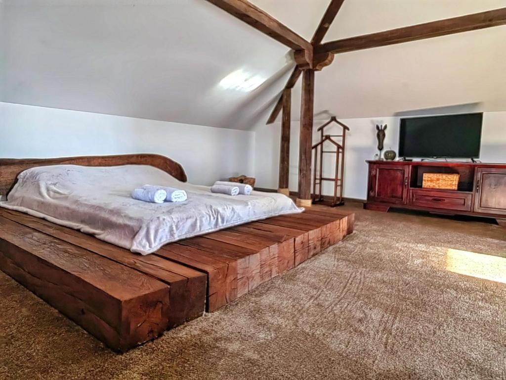 a bedroom with a wooden bed and a flat screen tv at Еко Комплекс Албиция in Gospodinovo