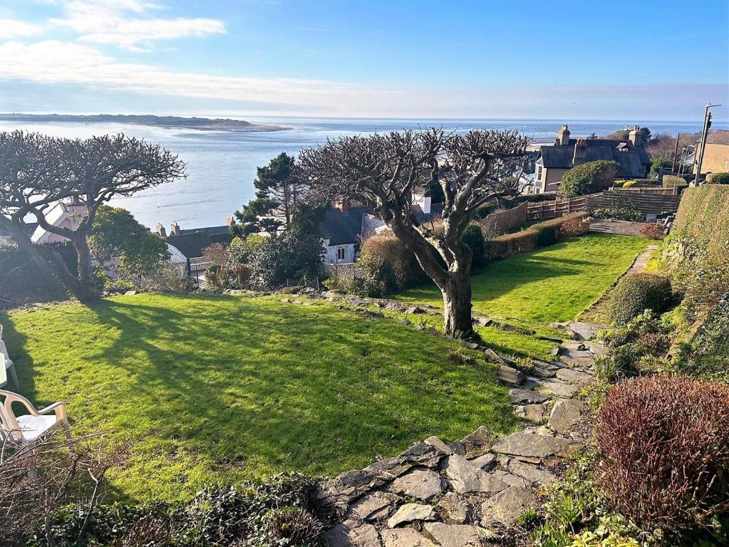 a green yard with trees and the ocean in the background at 5 Bed in Aberdovey 90493 in Aberdyfi