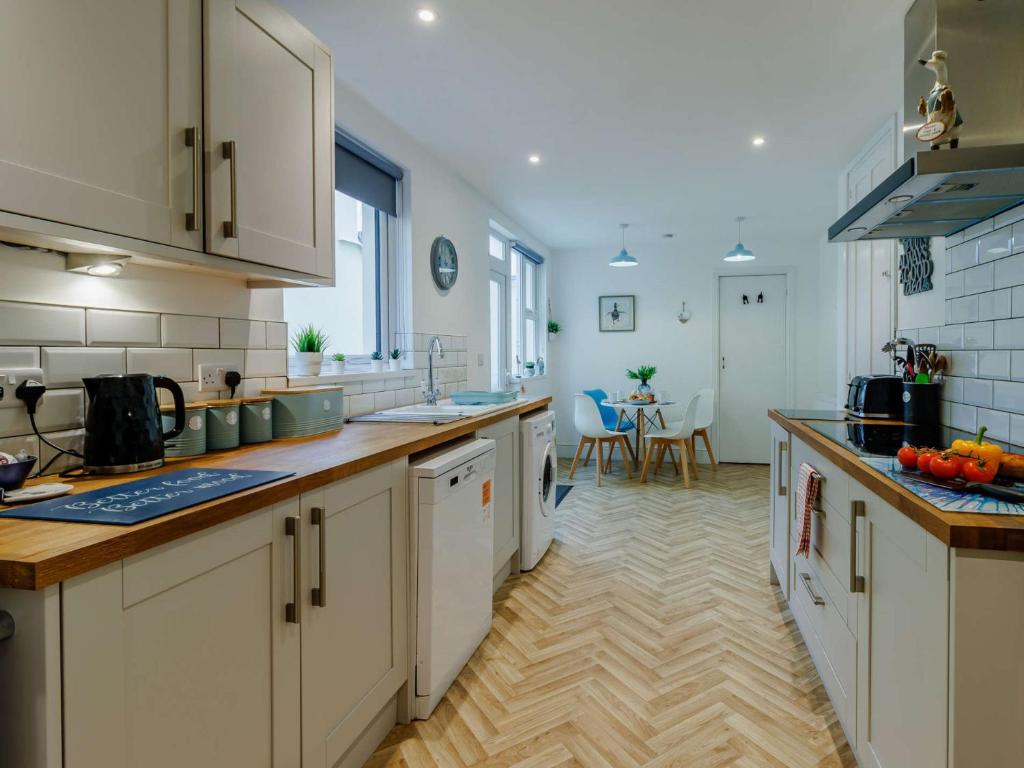 a kitchen with white cabinets and a wooden floor at 4 Bed in Brixham 90449 in Brixham