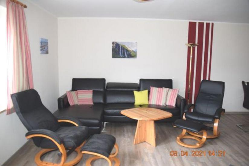 una sala de estar con un sofá de cuero negro y sillas en Ferienwohnung - W52b EG, en Lemkendorf