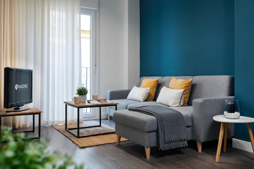 ein Wohnzimmer mit einem Sofa und einem TV in der Unterkunft Espíritu Santo Suite Apartment in Sevilla