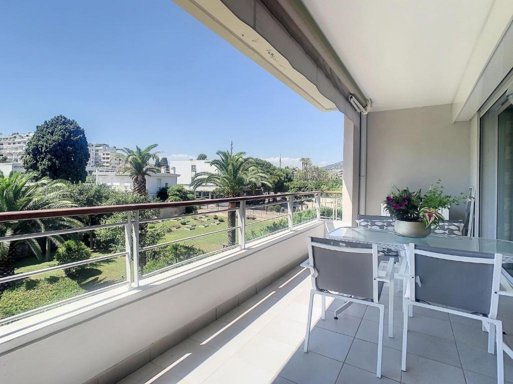 un balcon avec une table et des chaises et une grande fenêtre dans l'établissement Cannes - 2 pièces quartier Palm Beach, à Cannes