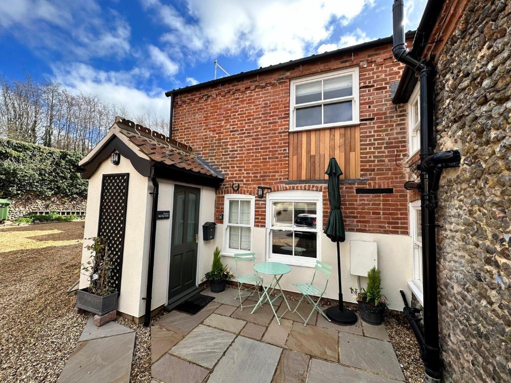 a brick house with a patio with a table and chairs at 1 Bed in Fakenham 90683 in Fakenham