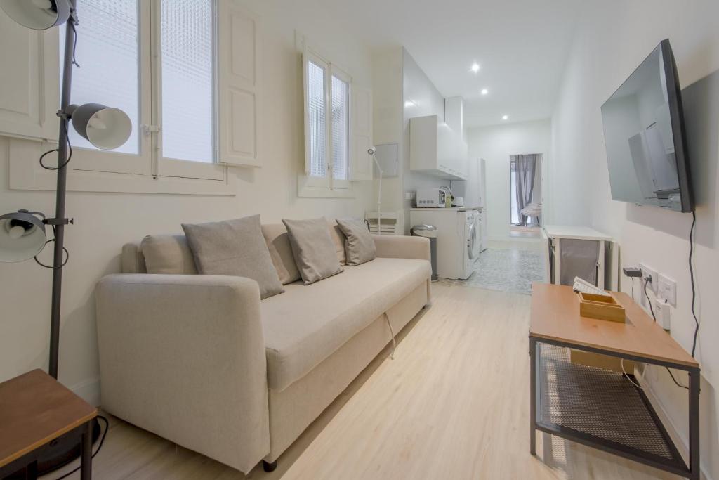Sala de estar blanca con sofá y mesa en Nuevo Apt para 7 pax en Malasana - Gran Via en Madrid